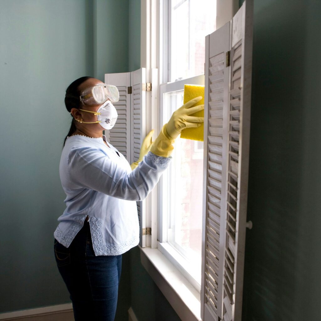 woman in white long sleeve shirt and blue denim jeans standing beside white wooden framed glass